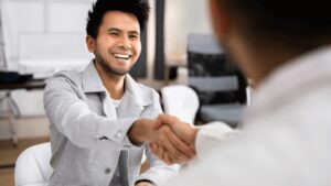 A person smiling and shaking hands during an interview.