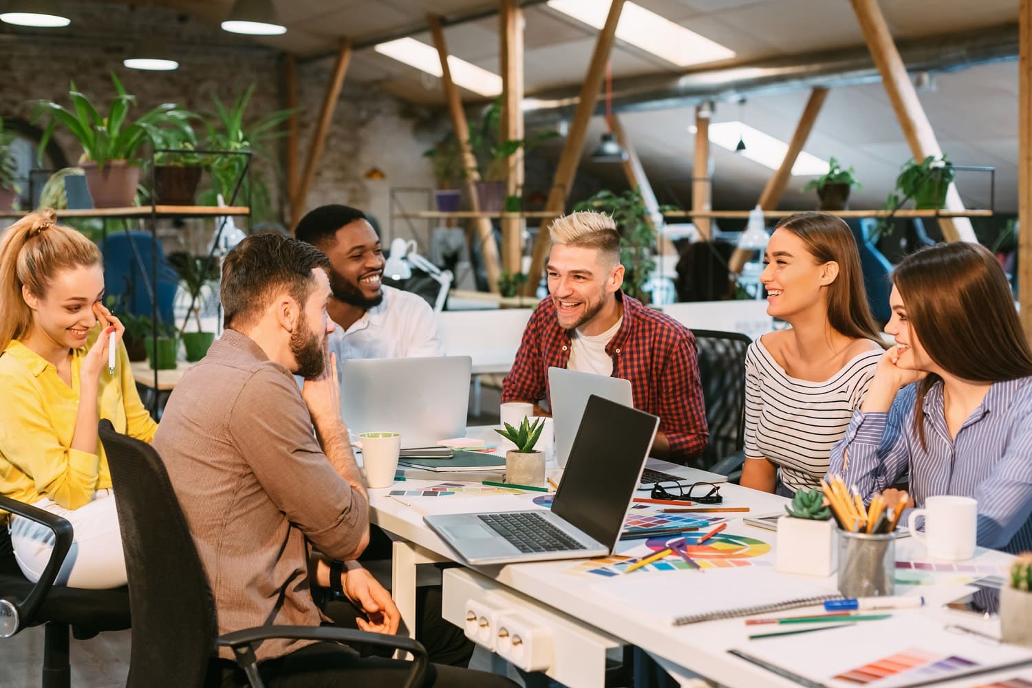 Colleagues smiling and discussing around a table in a modern office