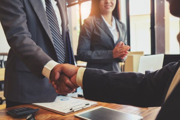 Two professionals shaking hands in a business meeting.