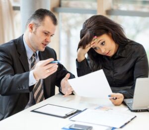 Two businesspeople discussing documents, one looking stressed