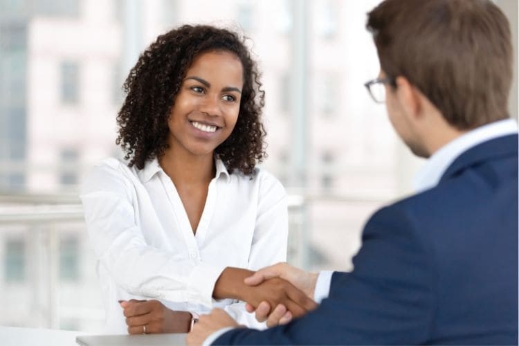 A smiling woman in a professional setting shaking hands with a man