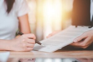 Close-up of two people reviewing and signing a contract document.