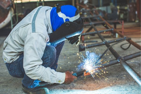 A welder working on a metal frame, producing bright sparks.