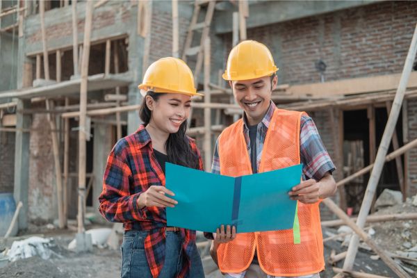 A male and female construction worker wearing safety helmets